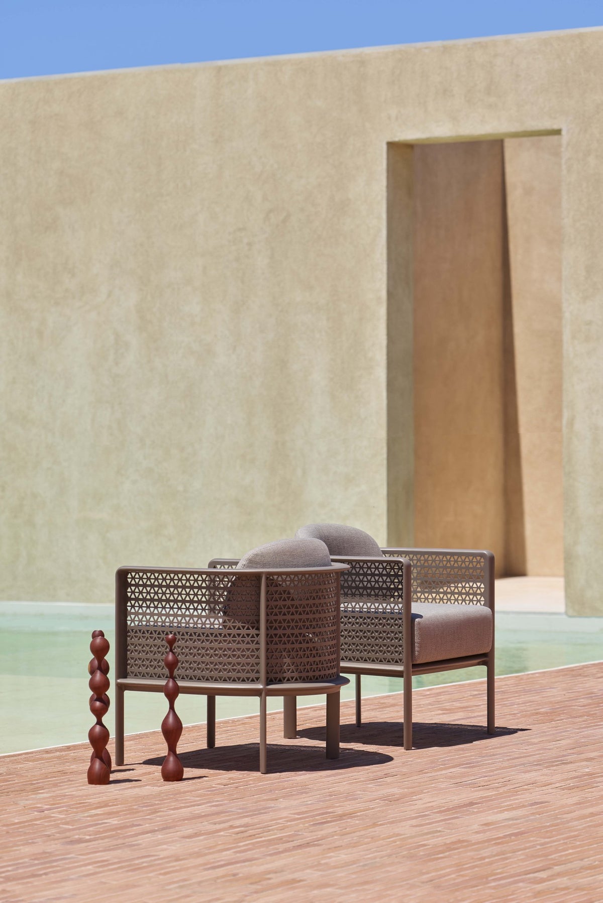 Gandia Blasco Arco Club Armchair in Bronze beside a pool