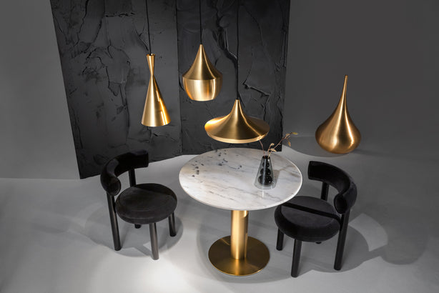 Tom Dixon Beat pendants in polished brass above a dining table