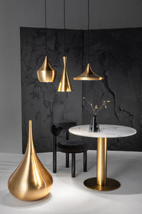 Tom Dixon Beat pendants in polished brass in a modern dining setting