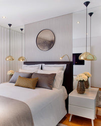 Tom Dixon Void Medium Pendant in polished brass beside a modern bed