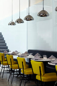 Tom Dixon Void Medium steel pendants above a modern dining area